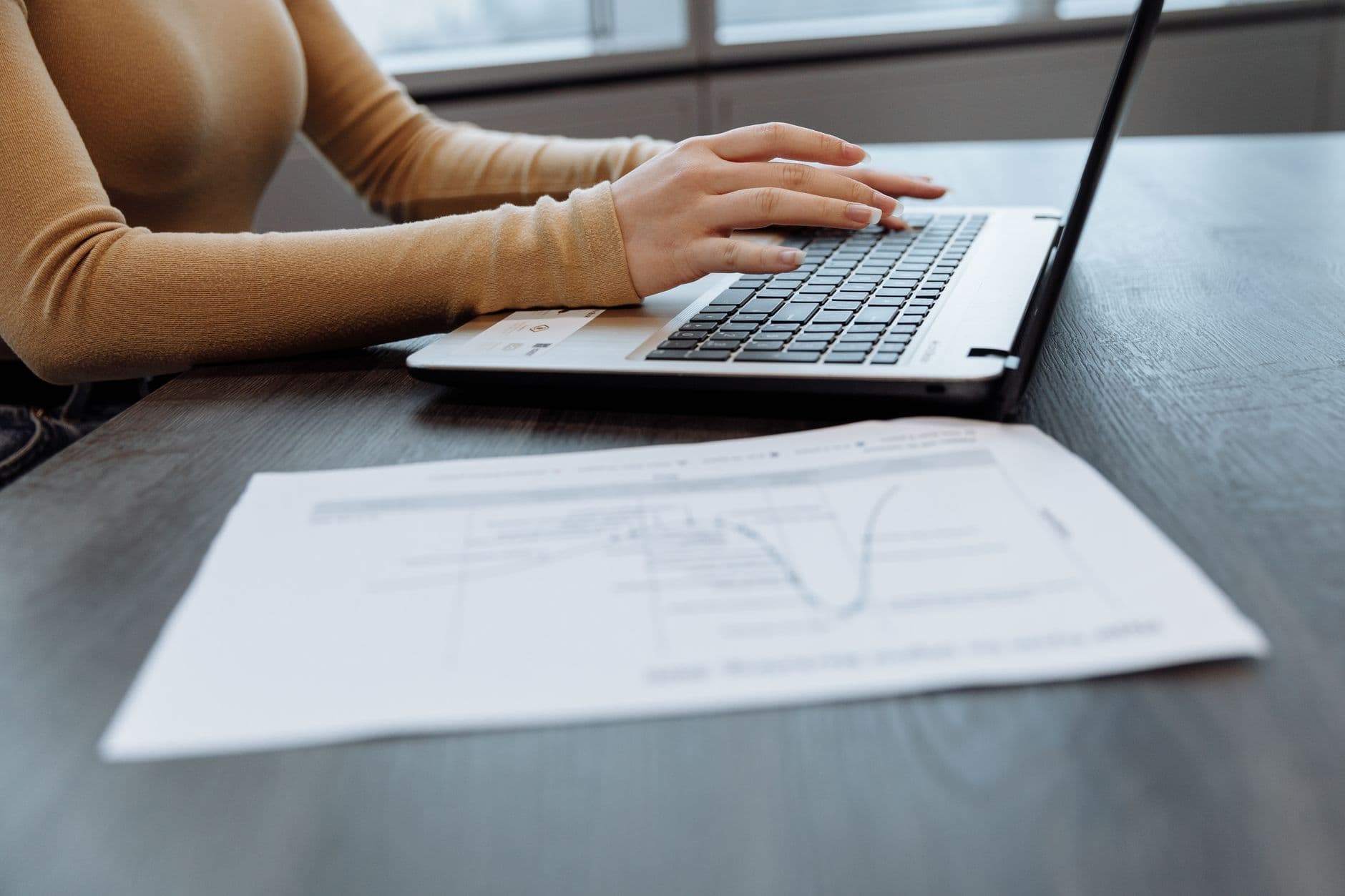 Administrativa de una pyme argentina revisando facturación y stock en una notebook en la oficina