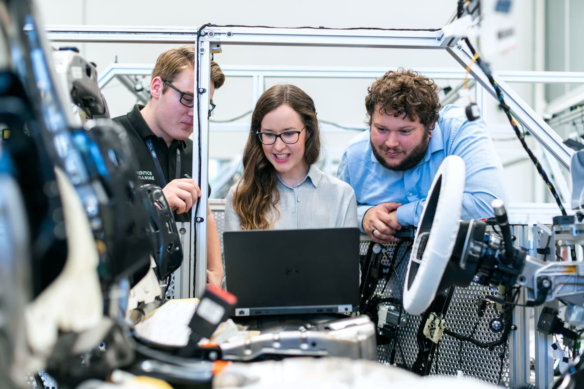 Tres personas revisando una computadora junto a equipos de un taller